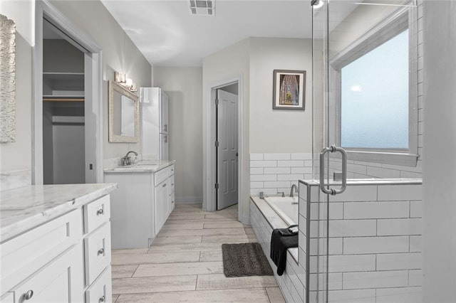 2060 Saint Denis St, New Orleans, LA 70122 - bathroom featuring two vanities, a bath, wood finished floors, and a stall shower