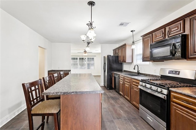 3211 Jackson Blvd, Chalmette, LA 70043 - kitchen with black appliances, a chandelier, a breakfast bar, a kitchen island, and pendant lighting
