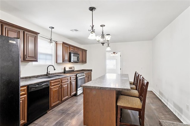 3211 Jackson Blvd, Chalmette, LA 70043 - kitchen with black appliances, a kitchen breakfast bar, a kitchen island, decorative light fixtures, and a chandelier