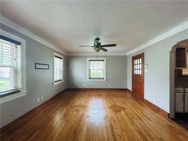 402 Orion Ave, Metairie, LA 70005 - unfurnished living room featuring a ceiling fan, arched walkways, wood finished floors, and crown molding