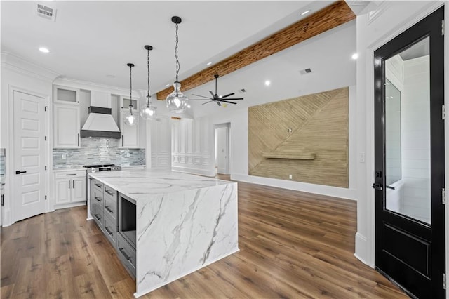 7717 Richard St, Metairie, LA 70003 - kitchen with premium range hood, white cabinetry, decorative light fixtures, wood finished floors, and recessed lighting