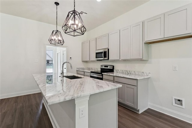 69206 4th Ave, Covington, LA 70433 - kitchen featuring appliances with stainless steel finishes, dark wood finished floors, an island with sink, light stone countertops, and gray cabinets