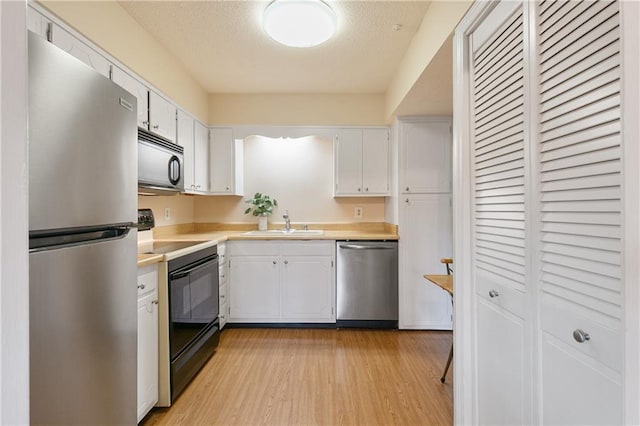 2700 Whitney Pl Unit 826, Metairie, LA 70002 - kitchen with appliances with stainless steel finishes, light countertops, white cabinets, light wood finished floors, and a textured ceiling