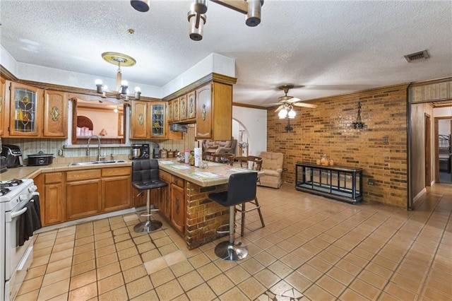 1319 Sumner St, New Orleans, LA 70114 - kitchen with white range with gas cooktop, brown cabinetry, a ceiling fan, a textured ceiling, and glass insert cabinets