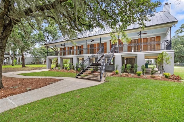 2801 Lakeshore Dr, Mandeville, LA 70448 - view of front of home with ceiling fan, stairway, a front yard, and a standing seam roof