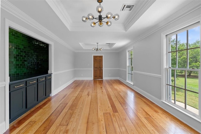 2801 Lakeshore Dr, Mandeville, LA 70448 - unfurnished living room featuring a chandelier, light wood-style flooring, a raised ceiling, and crown molding