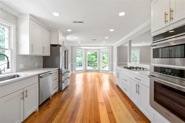 2801 Lakeshore Dr, Mandeville, LA 70448 - kitchen with stainless steel appliances, ornamental molding, plenty of natural light, white cabinets, and recessed lighting