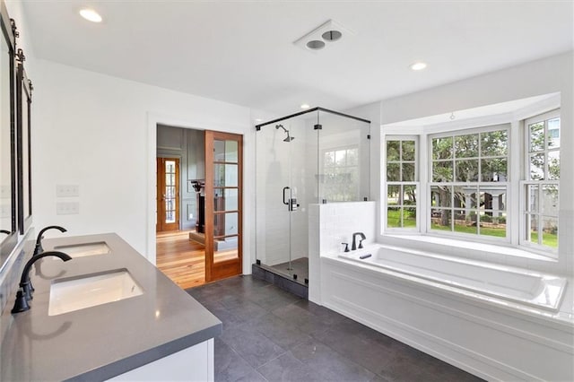 2801 Lakeshore Dr, Mandeville, LA 70448 - bathroom featuring a garden tub, double vanity, french doors, a stall shower, and healthy amount of natural light