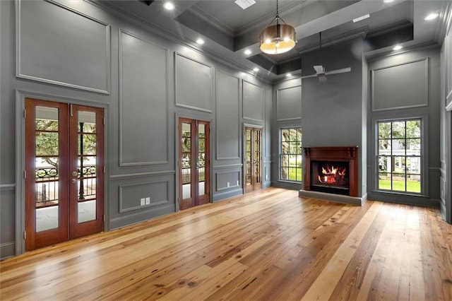 2801 Lakeshore Dr, Mandeville, LA 70448 - unfurnished living room featuring a decorative wall, french doors, ornamental molding, a warm lit fireplace, and plenty of natural light