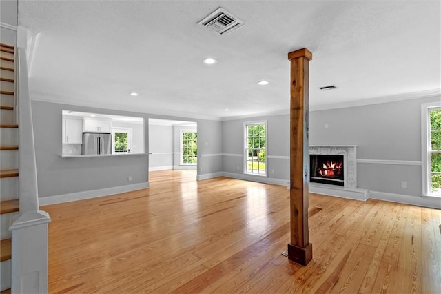 2801 Lakeshore Dr, Mandeville, LA 70448 - unfurnished living room featuring light wood-style flooring, a premium fireplace, recessed lighting, crown molding, and a textured ceiling