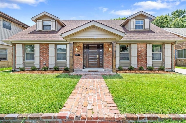 145 Macque Dr, Harahan, LA 70123 - cape cod house featuring a shingled roof, brick siding, and a front yard
