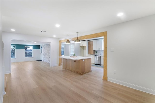 145 Macque Dr, Harahan, LA 70123 - kitchen with a kitchen island, light wood finished floors, light countertops, tasteful backsplash, and white cabinets