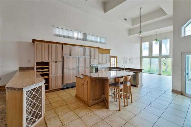 3128 Palm Vista Dr, Metairie, LA 70003 - kitchen featuring a high ceiling, a peninsula, stainless steel oven, a breakfast bar area, and light tile patterned floors