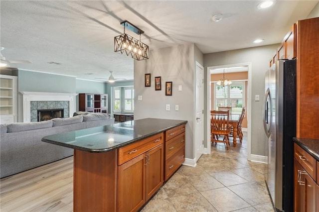 4808 Fairfield St, Metairie, LA 70006 - kitchen featuring freestanding refrigerator, a chandelier, brown cabinetry, a ceiling fan, and decorative light fixtures