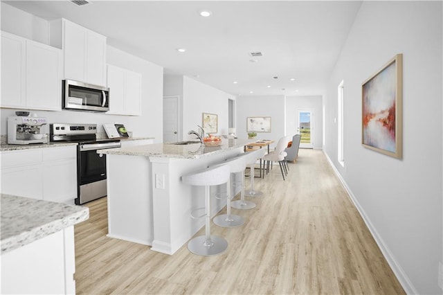 40447 Cara Mae St, Slidell, LA 70461 - kitchen featuring appliances with stainless steel finishes, light wood-style floors, a center island with sink, white cabinetry, and recessed lighting