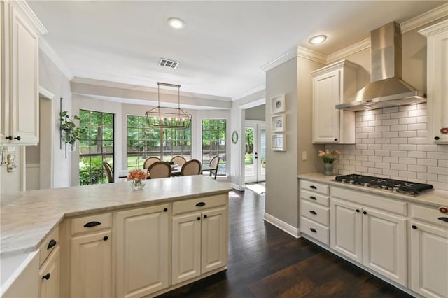 103 Century Oaks Ln, Mandeville, LA 70471 - kitchen with stainless steel gas stovetop, wall chimney range hood, backsplash, crown molding, and dark wood finished floors