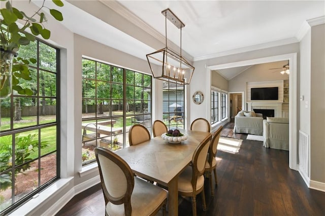 103 Century Oaks Ln, Mandeville, LA 70471 - dining room with a fireplace, dark wood-style flooring, crown molding, a chandelier, and lofted ceiling