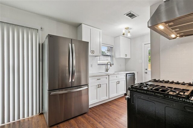 802 Claiborne Dr, Jefferson, LA 70121 - kitchen with appliances with stainless steel finishes, wall chimney exhaust hood, white cabinetry, dark wood-type flooring, and tasteful backsplash