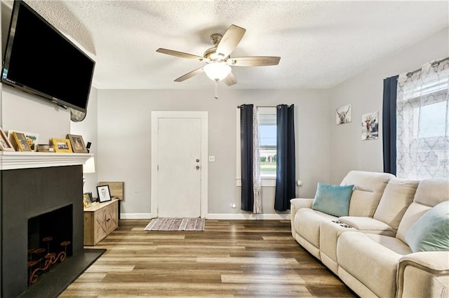 413 Fir St, La Place, LA 70068 - living room with a fireplace with raised hearth, healthy amount of natural light, wood finished floors, ceiling fan, and a textured ceiling