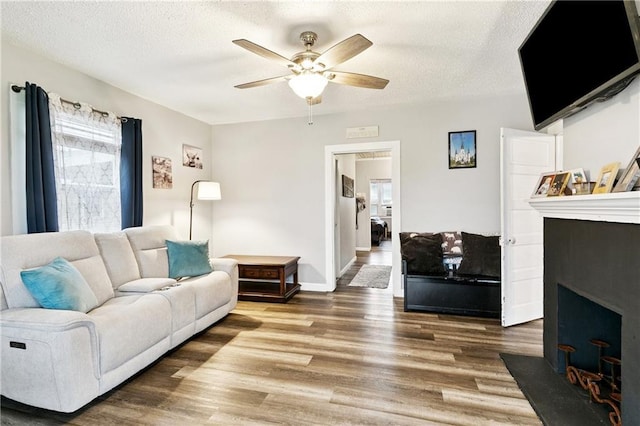 413 Fir St, La Place, LA 70068 - living area featuring a fireplace with flush hearth, ceiling fan, wood finished floors, and a textured ceiling