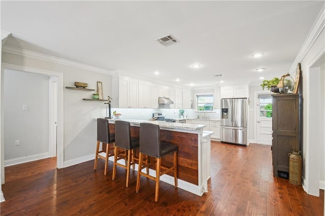 1213 Focis St, Metairie, LA 70005 - kitchen featuring stainless steel fridge, a peninsula, under cabinet range hood, stove, and white cabinetry