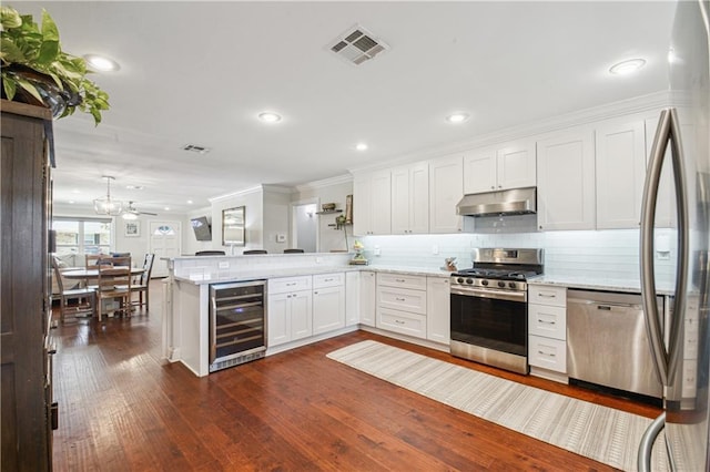 1213 Focis St, Metairie, LA 70005 - kitchen with stainless steel appliances, wine cooler, under cabinet range hood, a peninsula, and white cabinetry