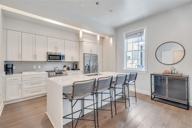 731 St Charles Ave Unit 304, New Orleans, LA 70130 - kitchen featuring appliances with stainless steel finishes, light wood finished floors, a kitchen bar, and white cabinets