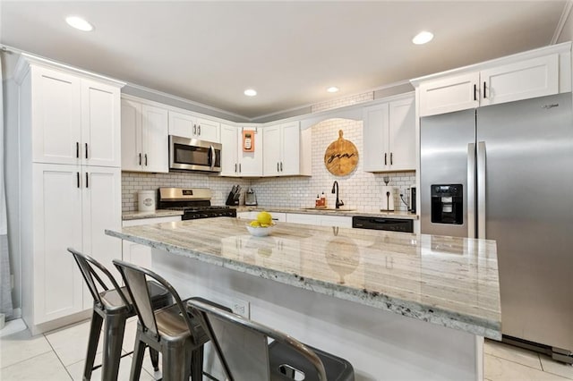 917 Ellen St, Terrytown, LA 70056 - kitchen with stainless steel appliances, light tile patterned floors, white cabinets, a kitchen breakfast bar, and recessed lighting