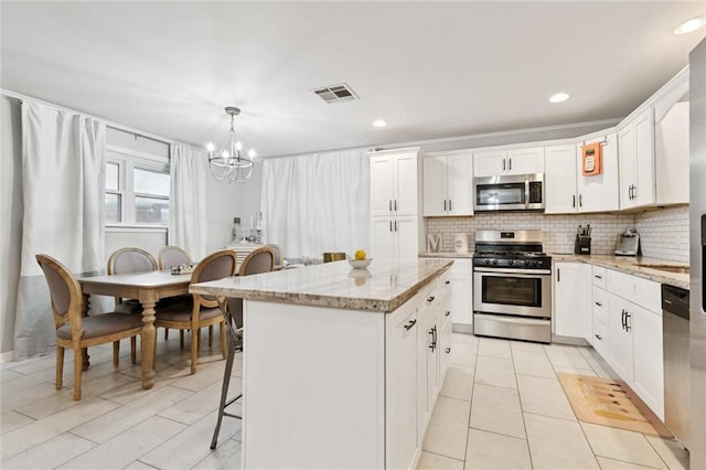 917 Ellen St, Terrytown, LA 70056 - kitchen with stainless steel appliances, a chandelier, a kitchen island, backsplash, and light stone countertops