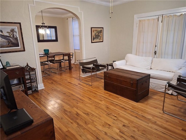 4712 Lafaye St, New Orleans, LA 70122 - living area with arched walkways, ornamental molding, light wood-style floors, and a chandelier