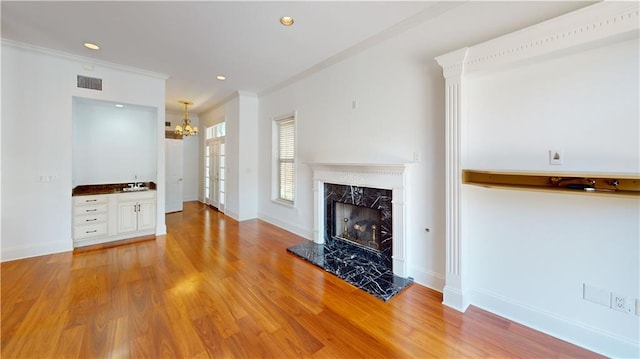 3739 N Hullen St, Metairie, LA 70002 - unfurnished living room featuring a high end fireplace, light wood-style flooring, a chandelier, crown molding, and recessed lighting