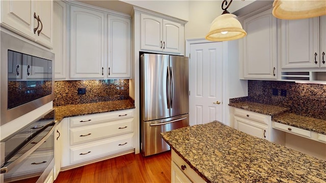 3739 N Hullen St, Metairie, LA 70002 - kitchen featuring freestanding refrigerator, dark stone counters, dark wood-type flooring, and backsplash