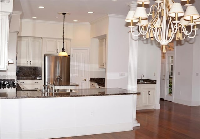 3739 N Hullen St, Metairie, LA 70002 - kitchen featuring freestanding refrigerator, dark stone countertops, a peninsula, backsplash, and ornamental molding