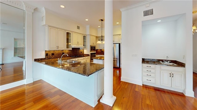 3739 N Hullen St, Metairie, LA 70002 - kitchen featuring appliances with stainless steel finishes, dark stone counters, wood finished floors, tasteful backsplash, and a peninsula