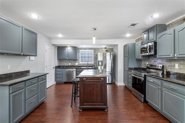 1200 Waltham St, Metairie, LA 70001 - kitchen featuring stainless steel appliances, decorative backsplash, gray cabinetry, a kitchen island, and dark wood finished floors