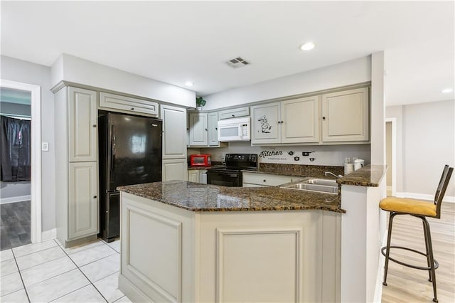 4925 Rhodes Dr, New Orleans, LA 70126 - kitchen with black appliances, a peninsula, dark stone countertops, gray cabinetry, and recessed lighting