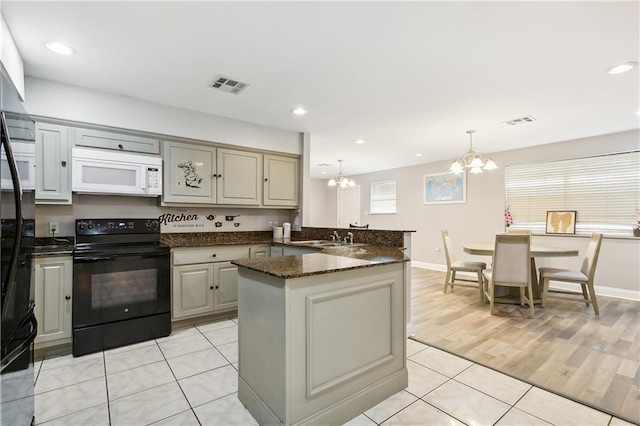 4925 Rhodes Dr, New Orleans, LA 70126 - kitchen with white microwave, black range with electric cooktop, a chandelier, light tile patterned flooring, and a peninsula