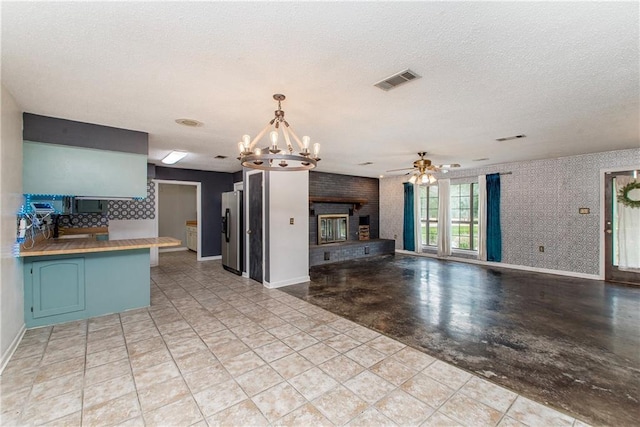 2129 Hamilton St, Franklinton, LA 70438 - kitchen featuring stainless steel appliances, a chandelier, a textured ceiling, a brick fireplace, and ceiling fan