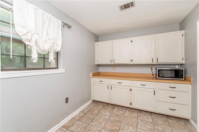 2129 Hamilton St, Franklinton, LA 70438 - kitchen with stainless steel microwave, a textured ceiling, light countertops, and white cabinets