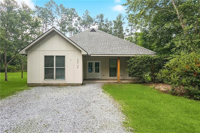 22562 2nd St, Mandeville, LA 70471 - view of front of property featuring a shingled roof, french doors, a front yard, board and batten siding, and gravel driveway
