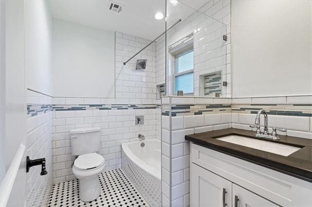 7109 Dreux Ave, New Orleans, LA 70126 - full bathroom featuring tile walls, vanity, shower / washtub combination, tile patterned floors, and wainscoting