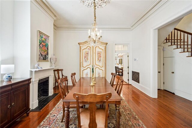 1128 Fourth St, New Orleans, LA 70130 - dining space with stairs, a chandelier, dark wood finished floors, ornamental molding, and a fireplace with raised hearth