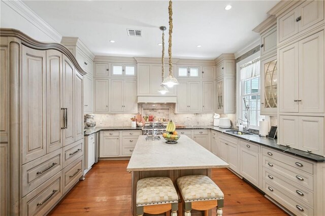 1128 Fourth St, New Orleans, LA 70130 - kitchen featuring a breakfast bar area, glass insert cabinets, a center island, decorative light fixtures, and recessed lighting