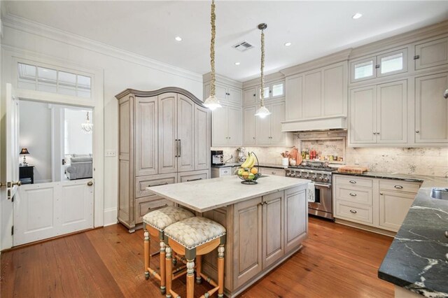 1128 Fourth St, New Orleans, LA 70130 - kitchen with stainless steel range, a kitchen island, wood finished floors, tasteful backsplash, and recessed lighting