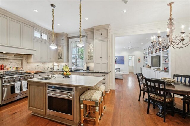 1128 Fourth St, New Orleans, LA 70130 - kitchen with stainless steel appliances, a chandelier, glass insert cabinets, an island with sink, and recessed lighting