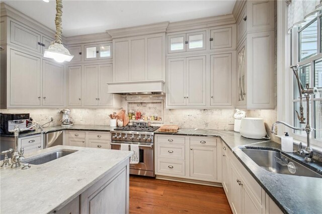 1128 Fourth St, New Orleans, LA 70130 - kitchen featuring high end stove, wood finished floors, decorative backsplash, decorative light fixtures, and glass insert cabinets