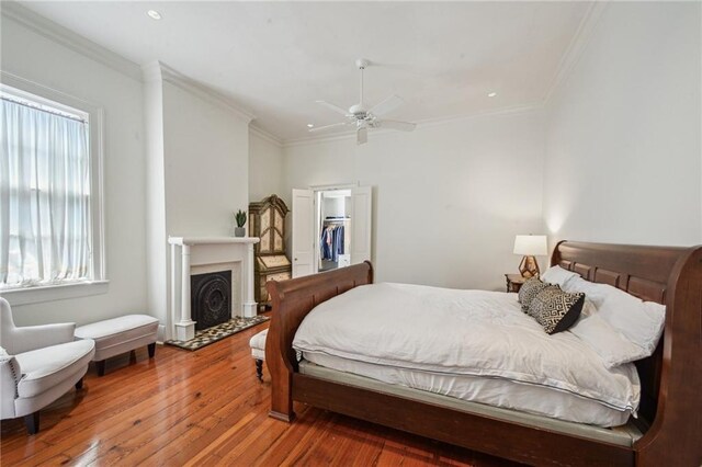 1128 Fourth St, New Orleans, LA 70130 - bedroom featuring hardwood / wood-style flooring, a walk in closet, crown molding, a fireplace with flush hearth, and a ceiling fan