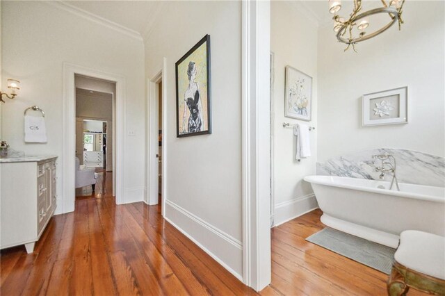 1128 Fourth St, New Orleans, LA 70130 - bathroom featuring ornamental molding, a chandelier, a soaking tub, vanity, and wood finished floors