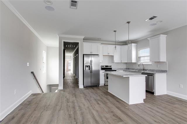 1704-1706 S Dupre St, New Orleans, LA 70125 - kitchen featuring stainless steel appliances, ornamental molding, white cabinets, a kitchen island, and light countertops