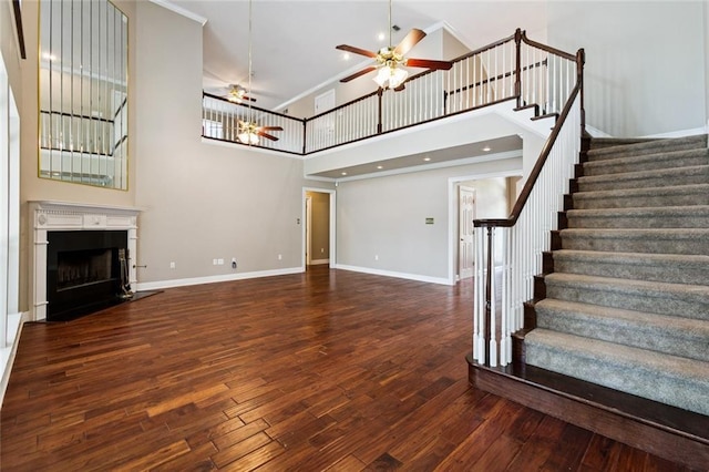 142 Colony Rd, Belle Chasse, LA 70037 - unfurnished living room with ceiling fan, stairs, wood finished floors, a high ceiling, and a fireplace with flush hearth